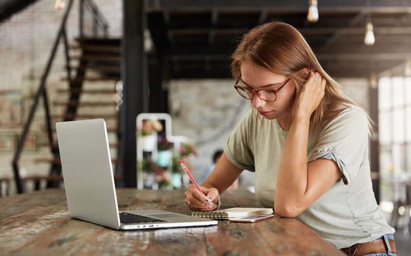 serious-female-student-concentrated-on-writing-28UG5RG.jpg